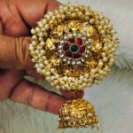 Traditional South Indian gold-finish Jada Billalu hair accessory with pearl detailing and red-green stone embellishments for bridal hairstyles